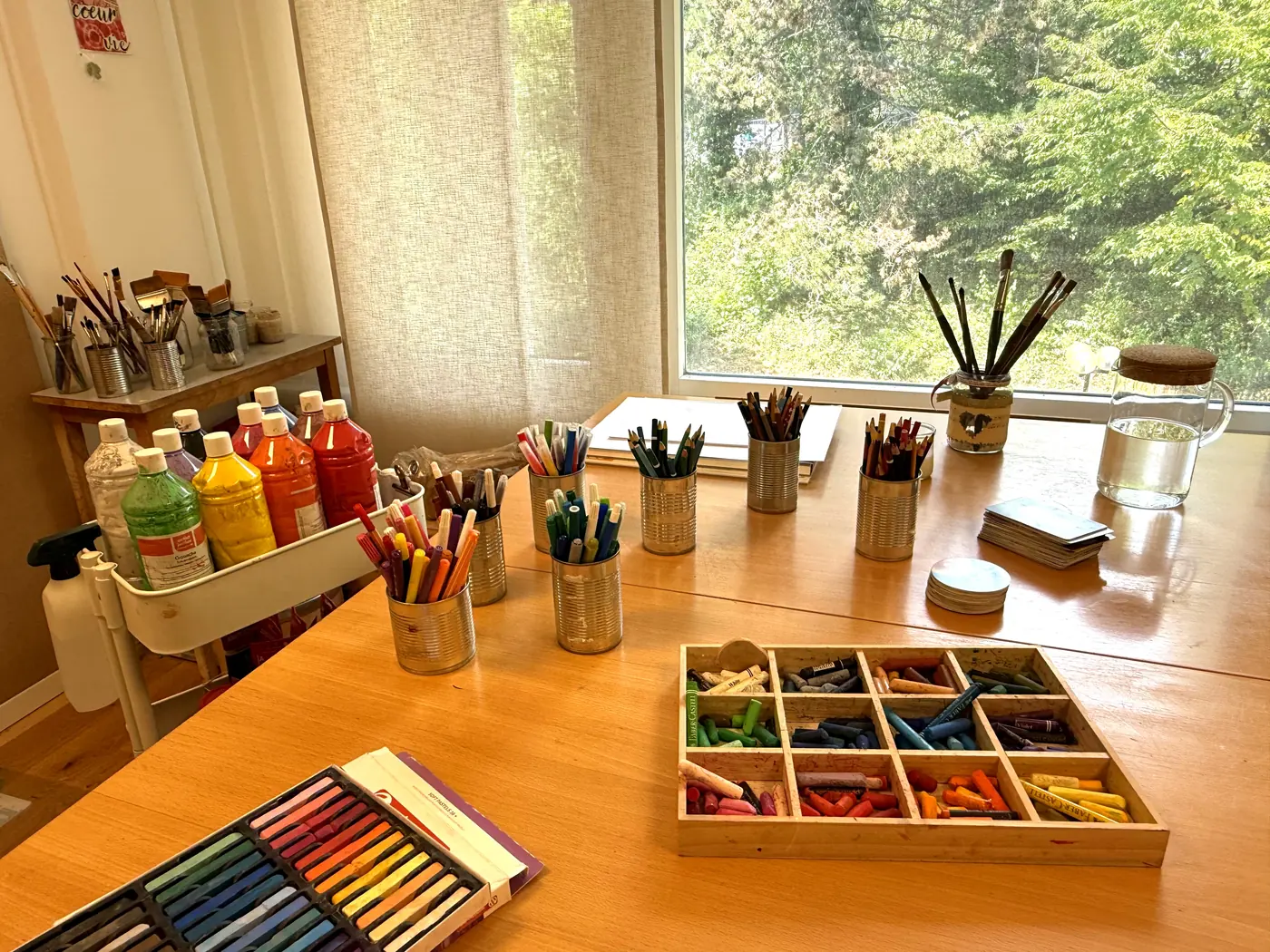 La table de travail de l'atelier, devant la fenêtre, avec pastels et pinceaux