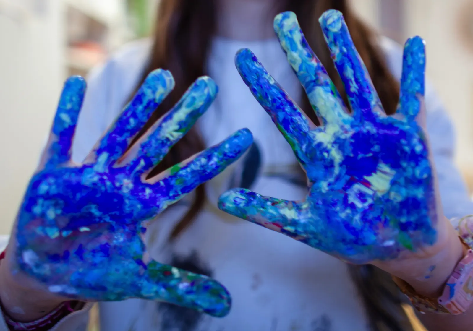 Les mains d'un enfant recouvertes de peinture bleue après une séance d'art-thérapie
